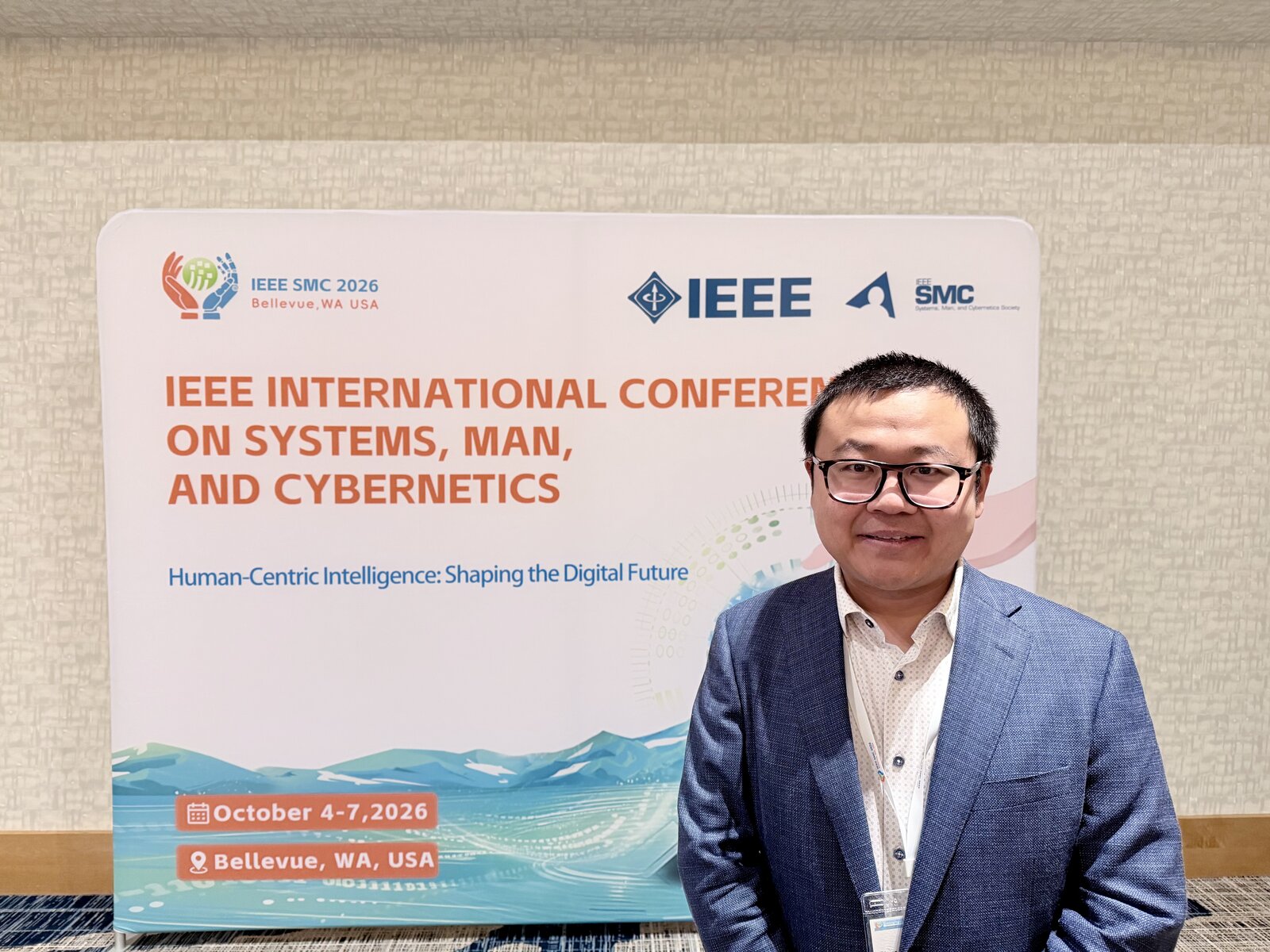 Dr. Steve Drew in front of the IEEE SMC 2026 banner in Bellevue, Washington
